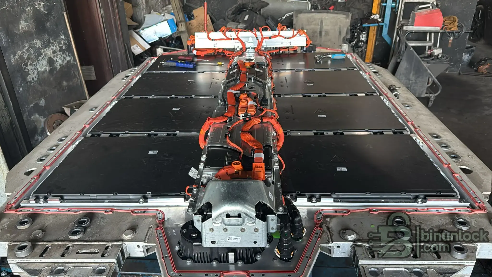 Removed BMW high-voltage battery pack showing internal cell modules and the SME unit connected via orange HV cabling.