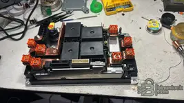 Disassembled BMW SME unit revealing internal components, copper busbars, and high-voltage safety terminals.