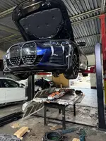 BMW electric vehicle on a shop lift with the entire high-voltage battery pack fully removed for SME module replacement.
