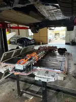 Detailed view of the dropped BMW EV battery pack positioned under the vehicle for Storage Management Electronics repair.